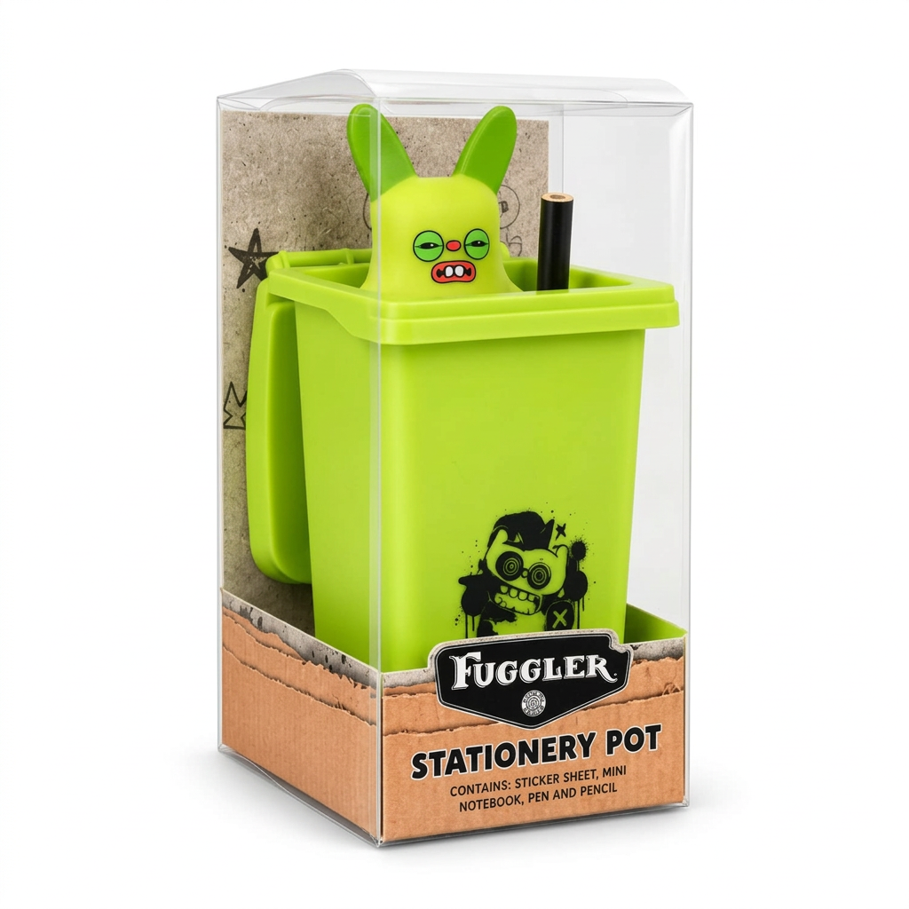Fuggler Stationery Pot in its clear plastic packaging, featuring a bright lime green trash can-shaped pot with a cartoonish green monster head popping out, a black pen, and a pencil inside.